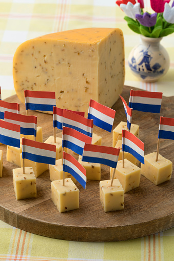 Pieces of traditional Dutch cumin cheese with a red, white and blue flag as a snack