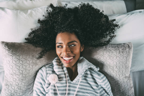 istock Beautiful black woman lying on bed looking at the camera smiling 940981720