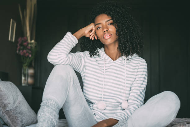 istock Beautiful thoughtful black woman sit on bed looking at the camera 940982212
