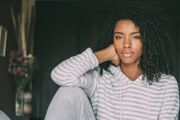 istock Beautiful thoughtful black woman sit on bed looking at the camera 940982302