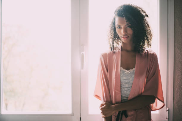 istock pretty black woman standing at the window 940982966