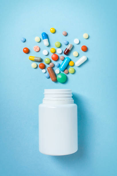 istock Assorted pharmaceutical medicine pills, tablets and capsules and bottle on blue background 940988908