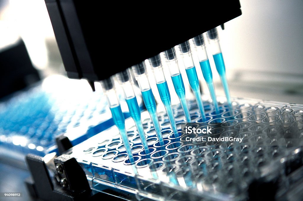 medical  research and pharmaceutical research : robotic pipette device Robotic multichannel pipette device portions out blue fluid for medical and pharmaceutical research and testing. Close-up. Laboratory Stock Photo