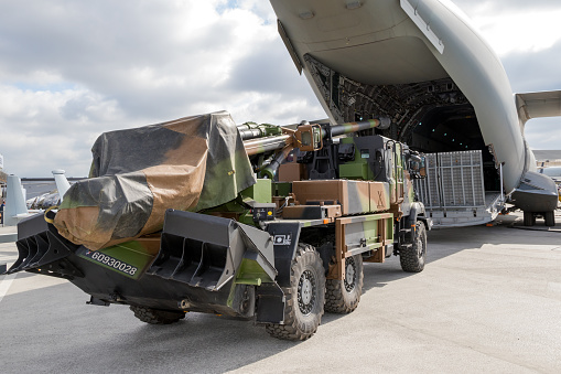 PARIS, FRANCE - JUN 23, 2017: Artillery truck in front of the loading door of an Airbus A400M military transport plane on display at the Paris Air Show 2017.