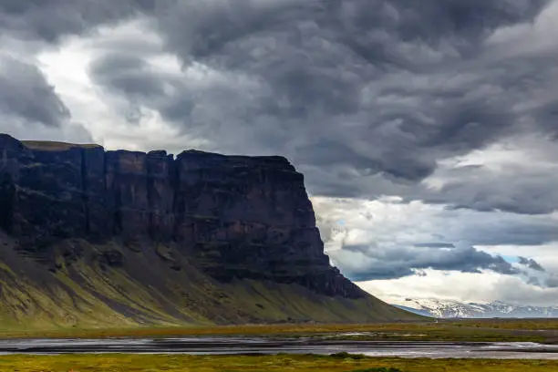 Photo of Large steep rock with grey cloud above, near to Kalfafell village, South Iceland