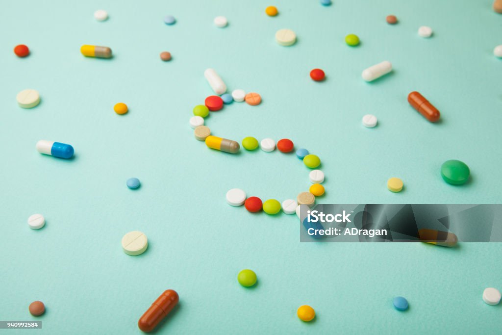 着色された丸薬と緑の背景のカプセルからお金ドルのシンボルです。高価な薬と医療保険 - 医薬品のロイヤリティフリーストックフォト