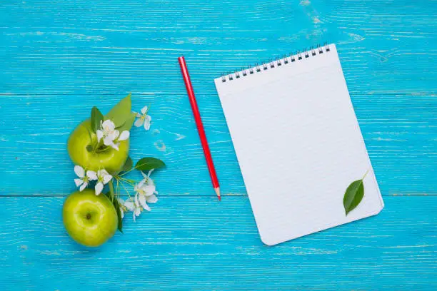 apple flowers and fruits with notepad over turquoise wooden planks