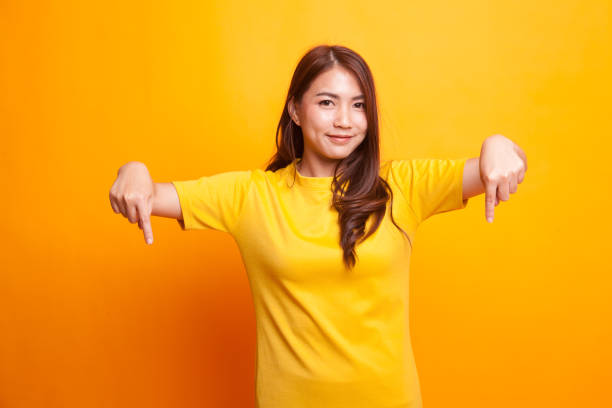 istock Beautiful young Asian woman point down to blank space. 941014400