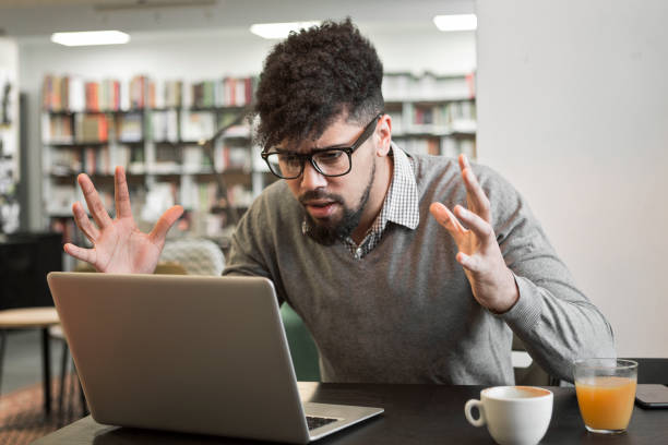 istock Young student getting frustrated over laptop in library 941014532