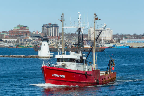 New Bedford, Massachusetts, USA - March 31, 2018: Fishing vessel Hunter with Palmer Island Light Station in background