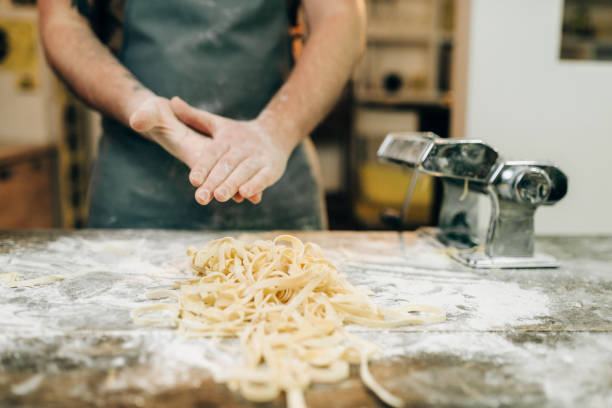 istock Chef against table with fettuccine, pasta machine 941021286