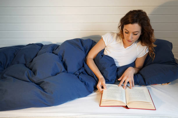 istock young woman reading book in bed 941029178