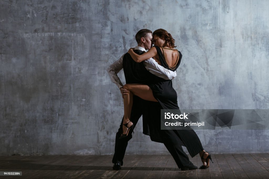 Young pretty woman in black dress and man dance tango Tango - Dance Stock Photo
