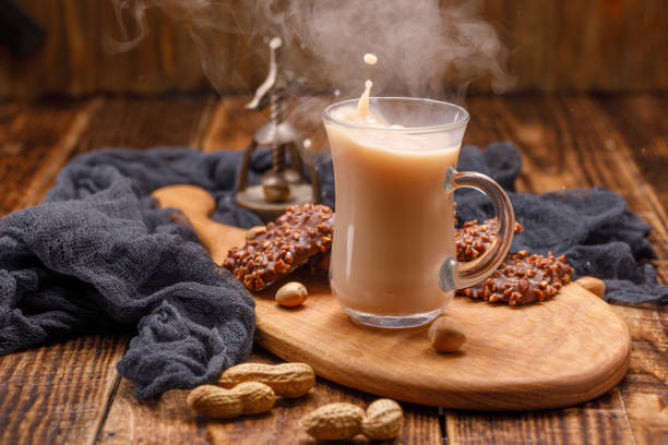 Tea with biscuits in a glass cup with a splash. Serve breakfast on a beautiful board with an antique walnut in the background. A smoking cup of tea in a wooden background.