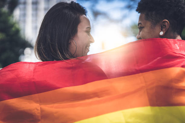 lesbisches paar mit regenbogenfahne - lesbian gay man rainbow multi colored stock-fotos und bilder