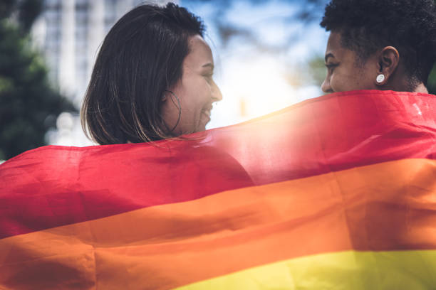 pareja de lesbianas con la bandera del arco iris - gay pride rainbow flag homosexual fotografías e imágenes de stock