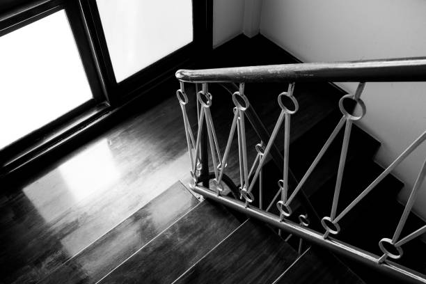 Dramatic black and white wooden stair way and metal hand rail in old house and sunlight shining through the window.