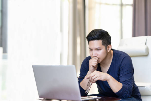 seriously confident asian young freelancer in smart casual working and concentrated on laptop sitting on desk in modern office ,co-working space or at home with copy space, webinar over the internet - ansiedade financeira imagens e fotografias de stock