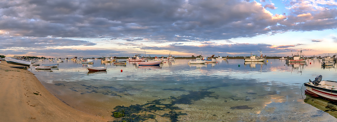 Panoramic view of fishing boats in Punta Umbria, Andalusia, Spain, and sunset reflections in the water.
