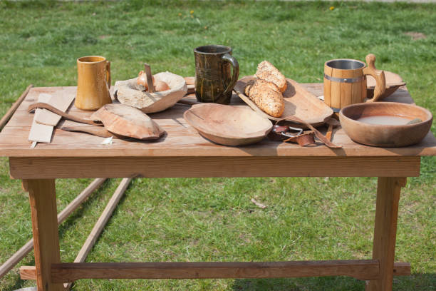 Table outside on a meadow with traditional wooden and ceramic dishes, bowls, beer mugs, tray, plates, spoon