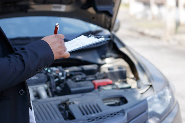 istock Side view of writing on clipboard while insurance agent examining car 941070778