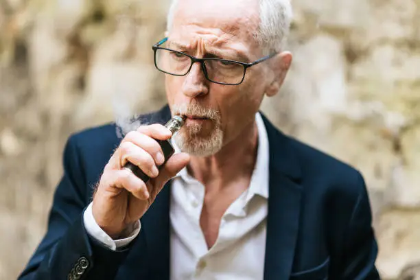 Portrait of mature man smoking electronic cigarette