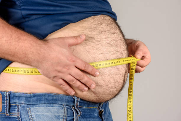 Overweight, Hairy Man Measuring His Belly with tape measure Overweight, Hairy Man Measuring His Belly with tape measure high quality and high resolution studio shoot hairy fat man pictures stock pictures, royalty-free photos & images