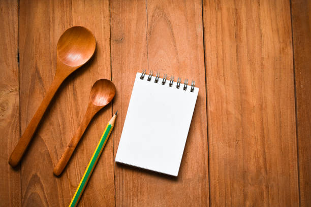 istock Notepad with pencil and spoon on wood board background.using wallpaper for education, business photo.Take note of the product for book with paper and concept, object or copy space. 941082056
