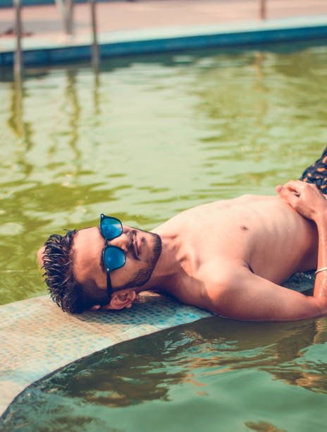 istock Asian Indian male relaxing by the pool. 941093098