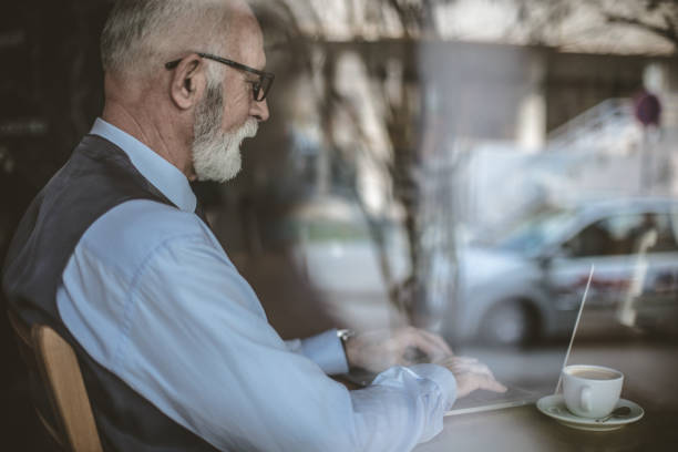 istock Senior businessman working on laptop. Image trough glass. 941093648