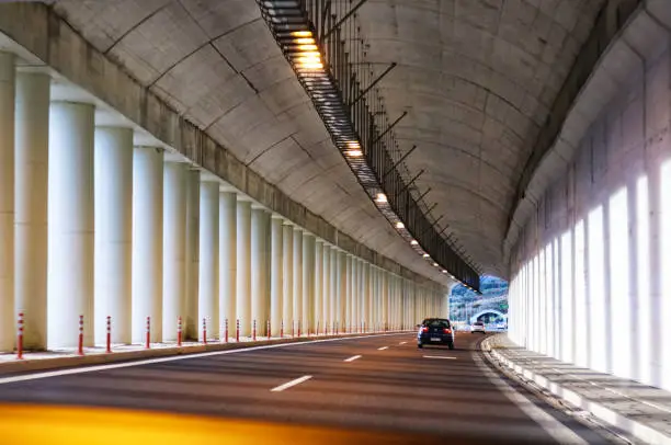 Photo of Mountainside highway tunnel with columns in Greece with another tunnel visible ahead