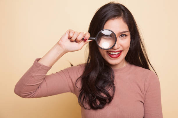 istock Young Asian woman with a magnifying glass. 941094678