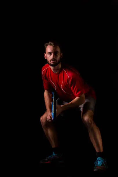 tennis player is waiting for a serve, he looks very serious. Low key photo with black background