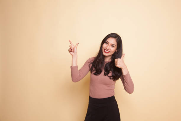 istock Young Asian woman point and thumbs up. 941097764