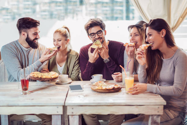 istock Young friends sharing pizza in a indoor cafe 941100472