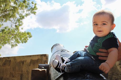 Six months old baby boy sitting on canon outdoor photo