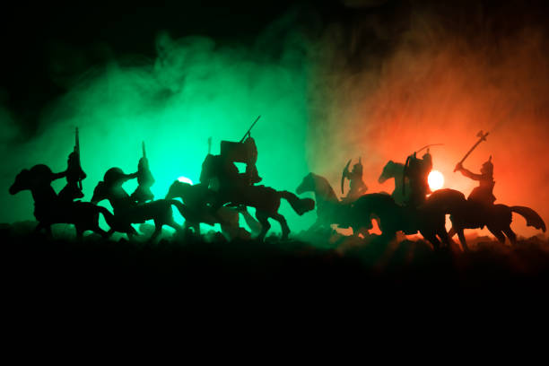 istock Medieval battle scene with cavalry and infantry. Silhouettes of figures as separate objects, fight between warriors on dark toned foggy background. Night scene. 941121828
