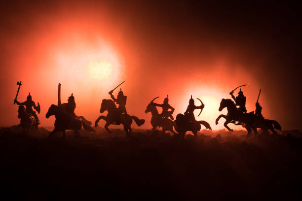 istock Medieval battle scene with cavalry and infantry. Silhouettes of figures as separate objects, fight between warriors on dark toned foggy background. Night scene. 941121848