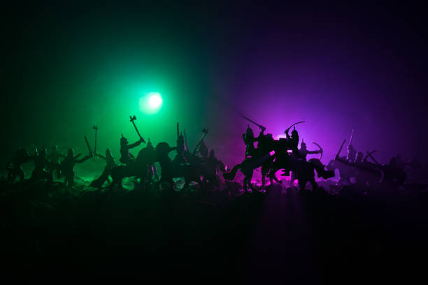 istock Medieval battle scene with cavalry and infantry. Silhouettes of figures as separate objects, fight between warriors on dark toned foggy background. Night scene. 941121882