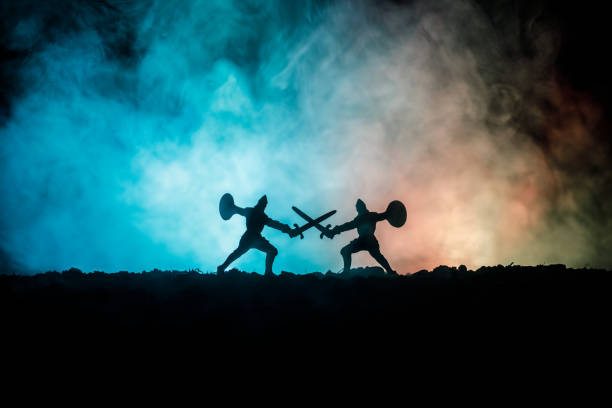 istock Medieval battle scene with cavalry and infantry. Silhouettes of figures as separate objects, fight between warriors on dark toned foggy background. Night scene. 941121910