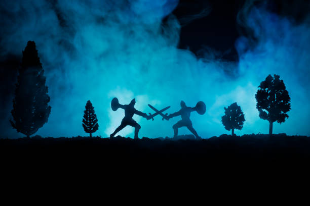 istock Medieval battle scene with cavalry and infantry. Silhouettes of figures as separate objects, fight between warriors on dark toned foggy background. Night scene. 941121912