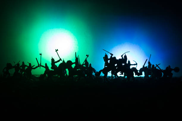 istock Medieval battle scene with cavalry and infantry. Silhouettes of figures as separate objects, fight between warriors on dark toned foggy background. Night scene. 941121922