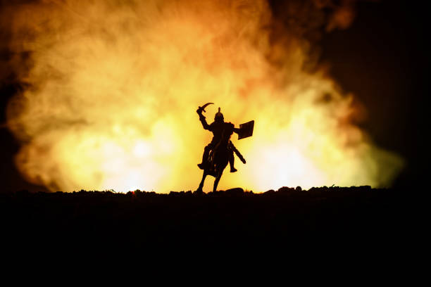 istock Medieval battle scene with cavalry and infantry. Silhouettes of figures as separate objects, fight between warriors on dark toned foggy background. Night scene. 941121926