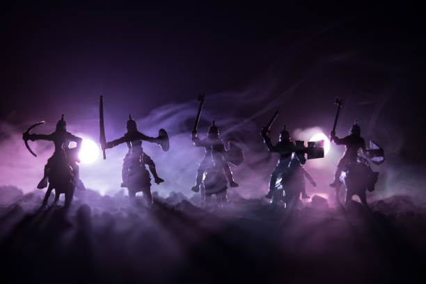 istock Medieval battle scene with cavalry and infantry. Silhouettes of figures as separate objects, fight between warriors on dark toned foggy background. Night scene. 941121928