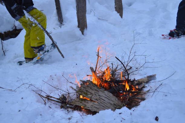 Campfire outside in winter time during snowshoes Making a fire during a winter hikes is always welcome in cold weather.  The heat of the flames allows the hikers to warm up and cook.  Interesting contrast between the heat of the flames et the coldness of the snow. snowshoeing snow shoe red stock pictures, royalty-free photos & images