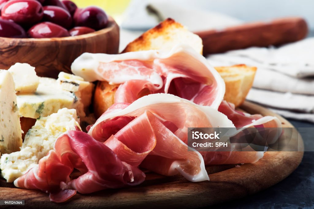 Snacks or antipasti, crostini, prosciutto, blue cheese and olives Snacks or antipasti, crostini, prosciutto, blue cheese and olives, gray background, selective focus Cheese Stock Photo