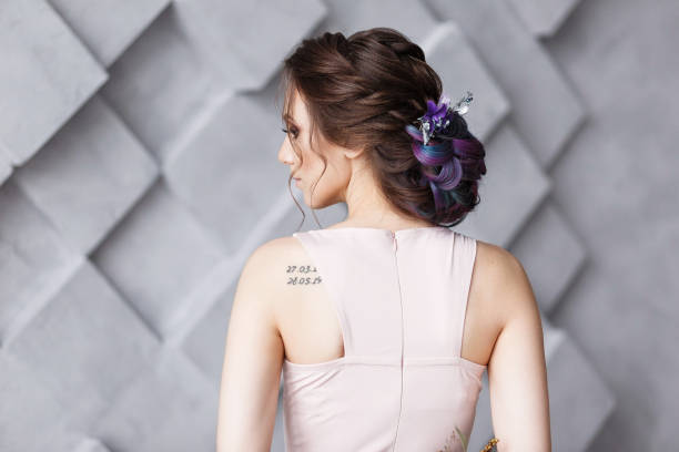 Brunette woman hairdo french twist, rear view on gray fashion studio background. Shoulder wit numeric tattoo Brunette woman hairdo french twist, rear view on gray fashion studio background. Shoulder wit numeric tattoo. back shoulder tattoos for women pictures stock pictures, royalty-free photos & images