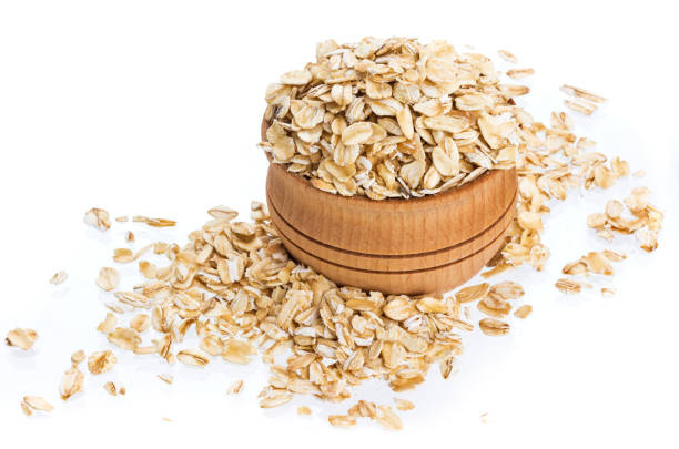 istock Oat flakes in wooden bowl isolated on white background 941125498