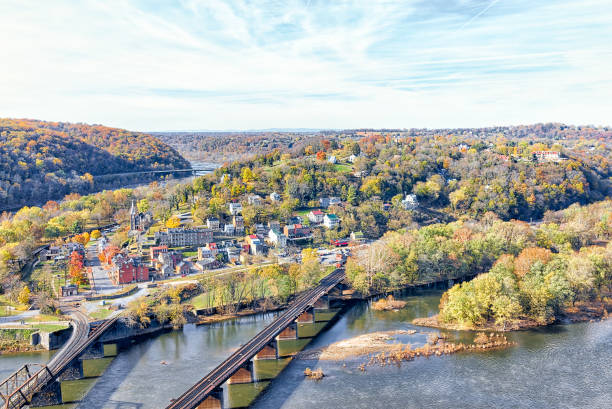 Harper's Ferry overlook with colorful orange yellow foliage fall autumn forest with small village town by river in West Virginia, WV Harper's Ferry overlook with colorful orange yellow foliage fall autumn forest with small village town by river in West Virginia, WV harpers ferry photos stock pictures, royalty-free photos & images