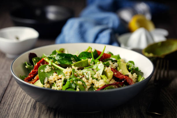 Healthy vegan quinoa spinach salad Home made freshness quinoa, spinach, avocado and sun dried tomatoes salad with pumpkin seeds and vinaigrette dressing salad bowl stock pictures, royalty-free photos & images